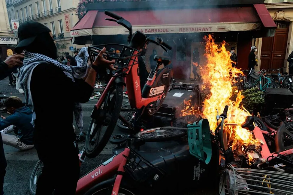 Primer ministro anuncia «toques de queda» en Francia tras disturbios y saqueos registrados en las grandes ciudades durante el fin de semana Un hombre arroja una bicicleta al fuego durante una protesta con disturbios y enfrentamientos con las fuerzas del orden cerca de la plaza de la República, en París, el 18 de octubre de 2026.